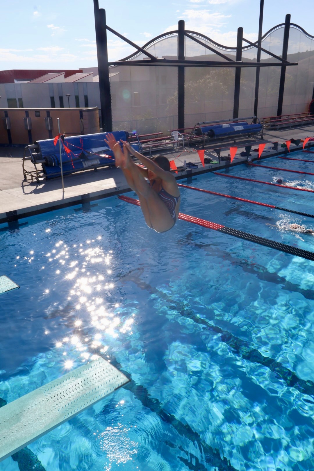High school diver in a tuck mid-flight off the springboard at Las Positas