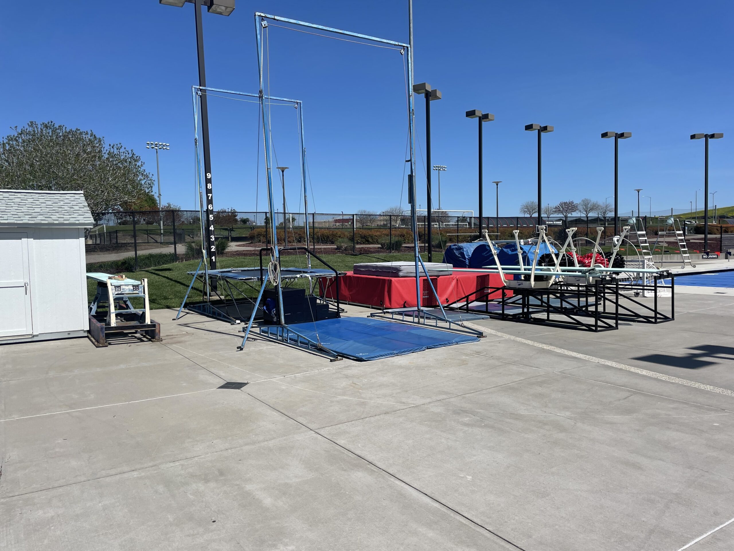 Dryland training area with spotting belt rig, trampoline, and dryboards on deck