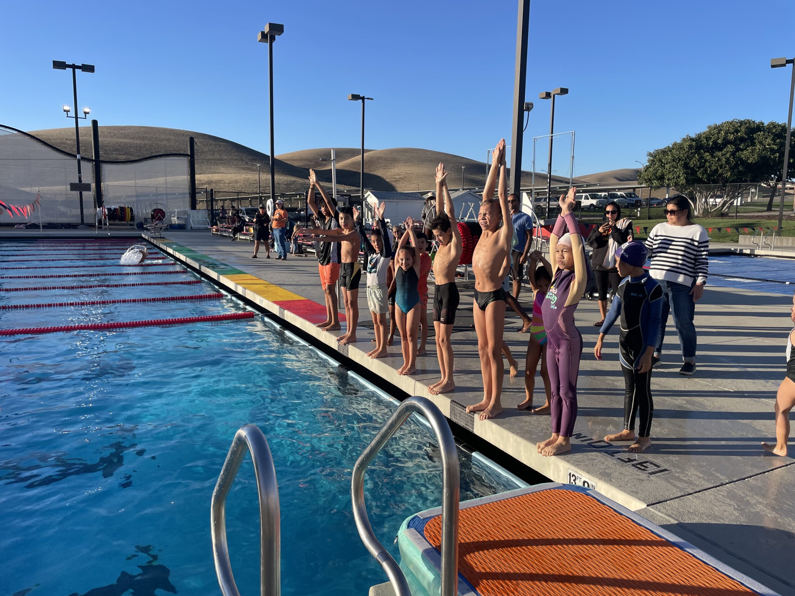 Summer dive camp participants lined up on deck practicing arm positions